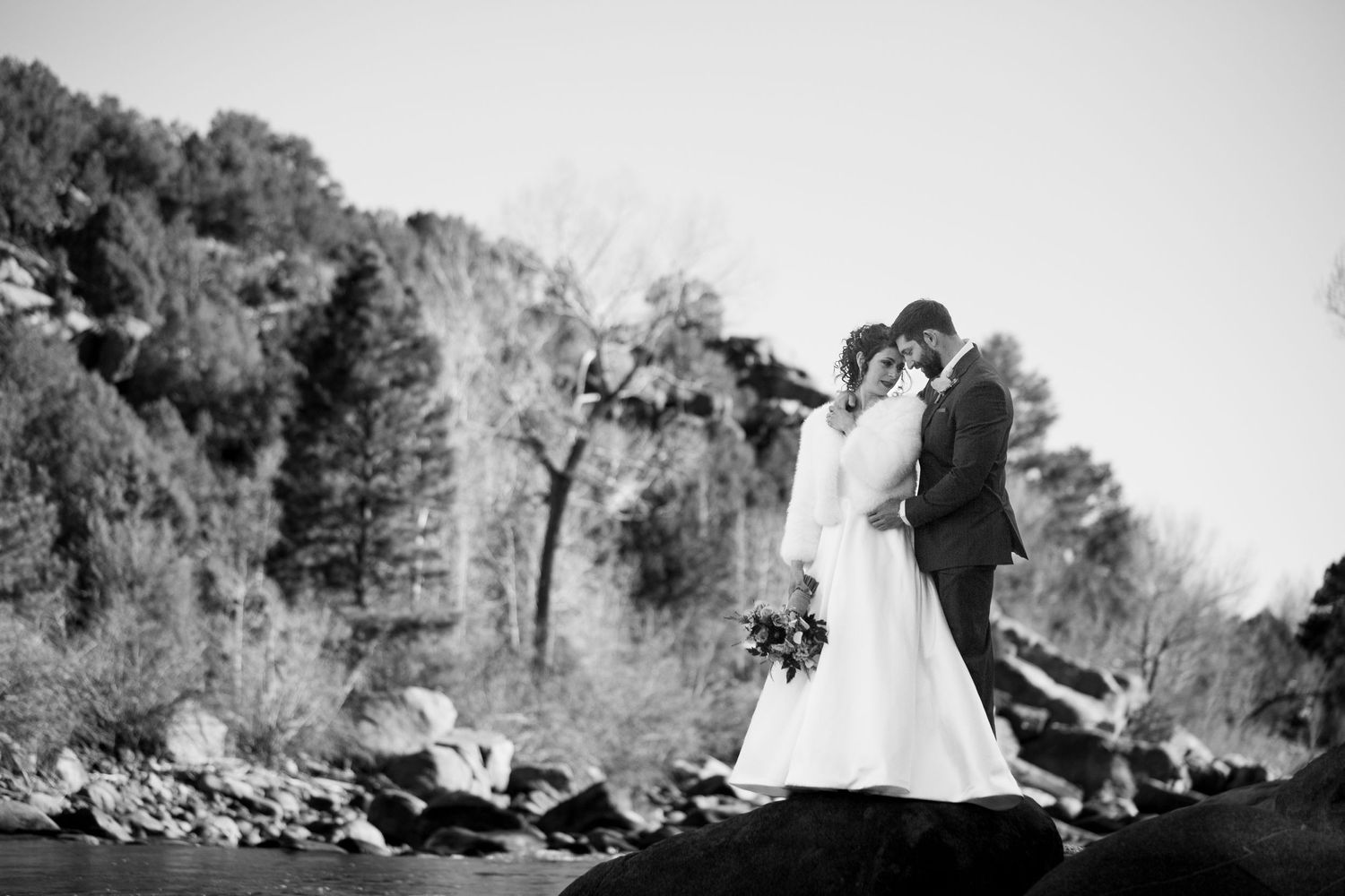 Black and white photo of couple on rocky outcrop in nature.