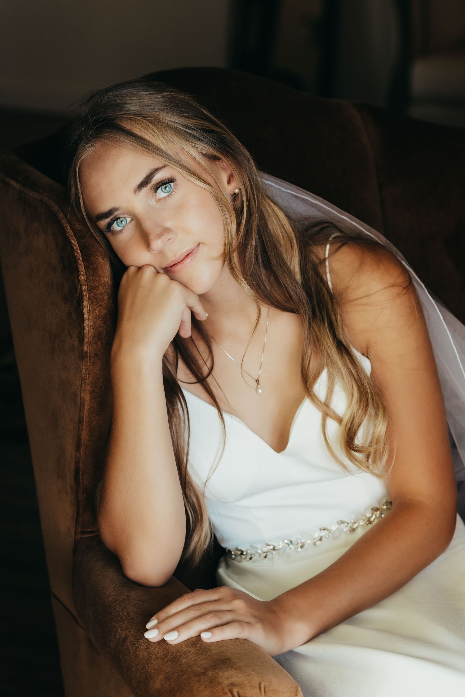 Interior portrait in warm lighting showing elegant white wedding dress and veil.