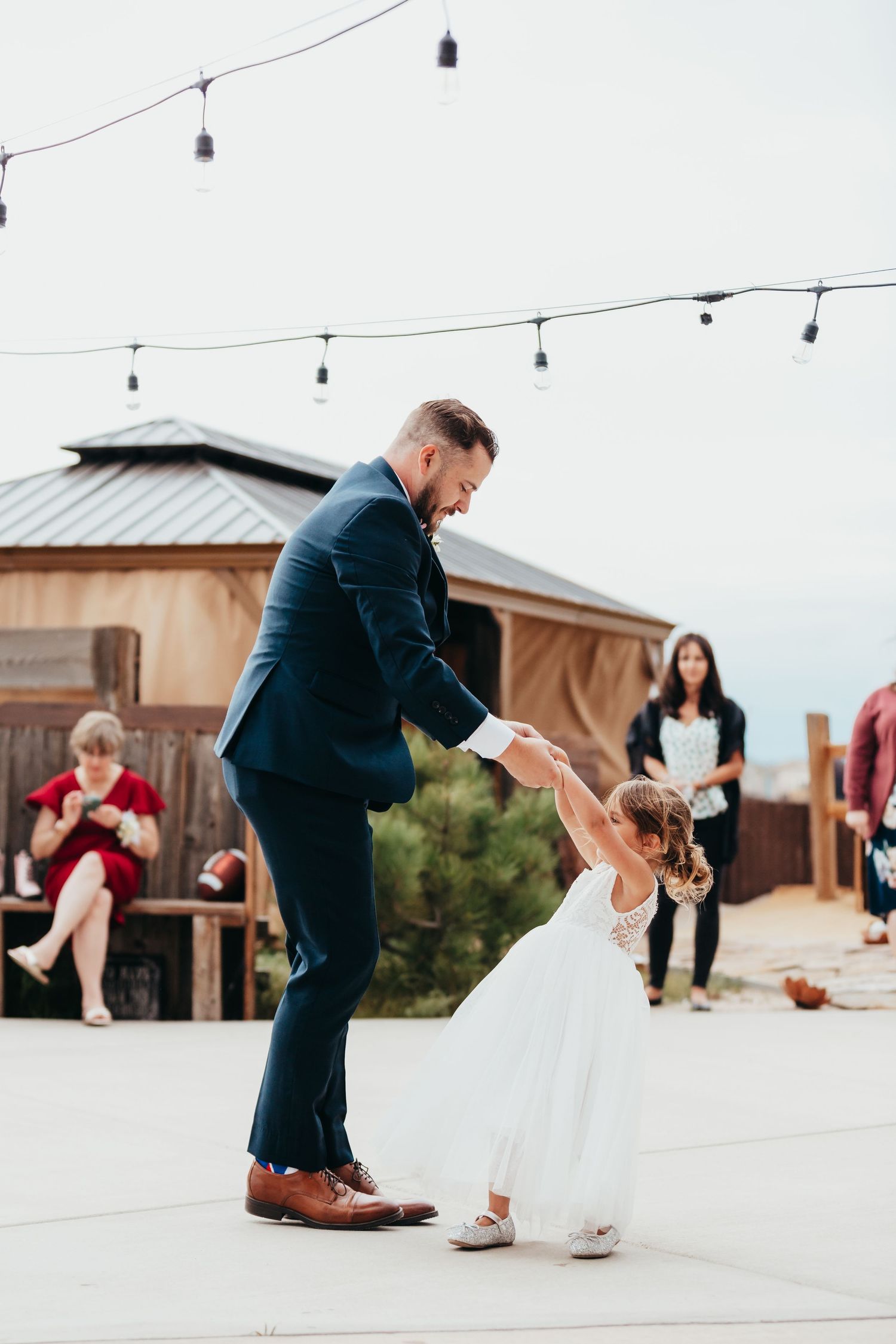 A sweet dance moment on an outdoor patio with string lights overhead.