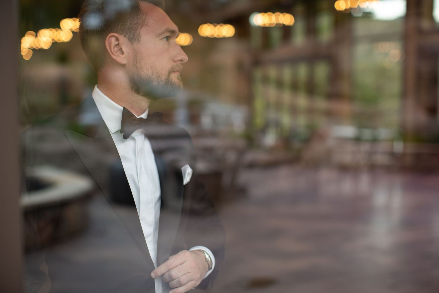 Profile view of formal attire through reflective window with bokeh lights.