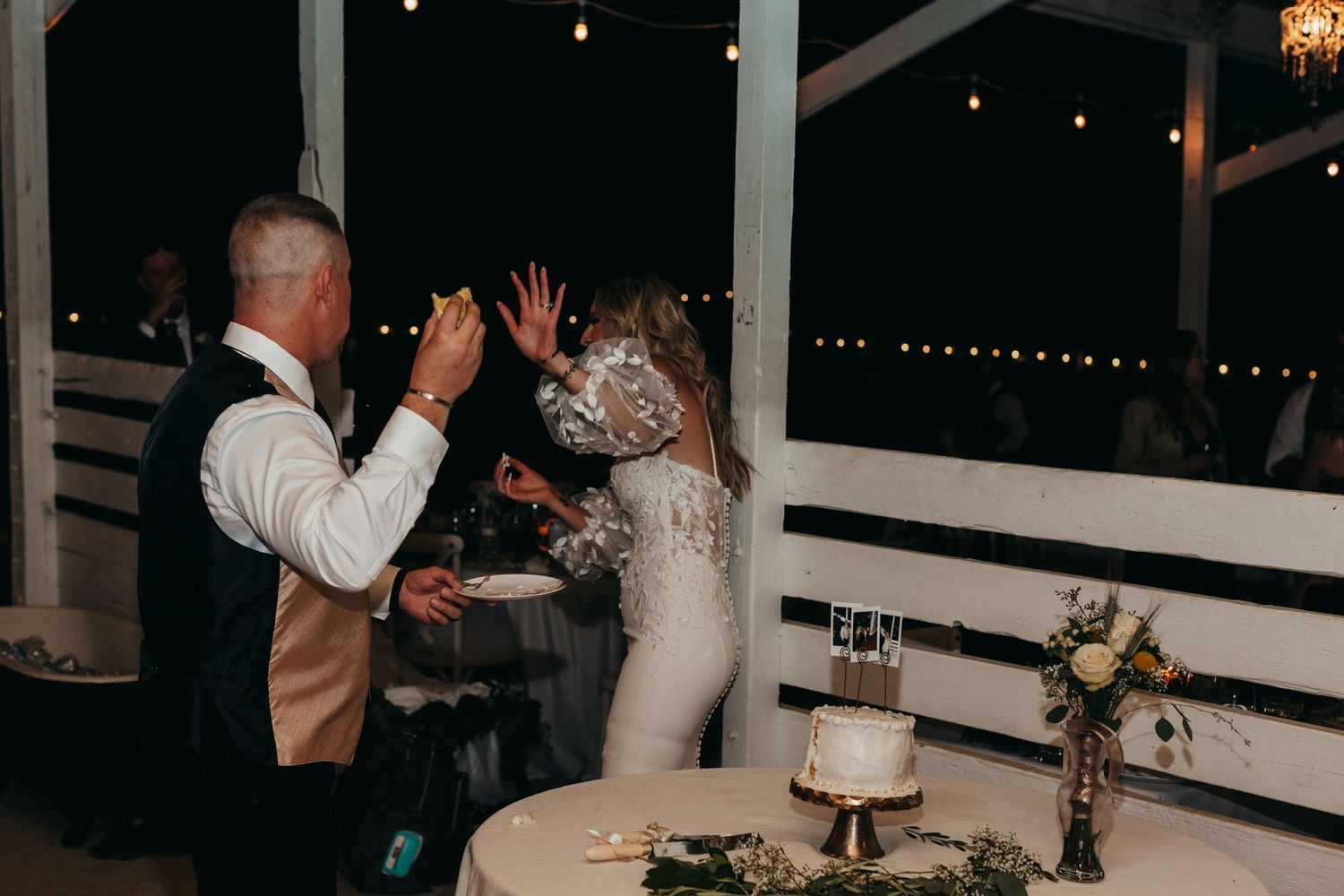 Wedding celebration moment during reception with white decor and string lights.