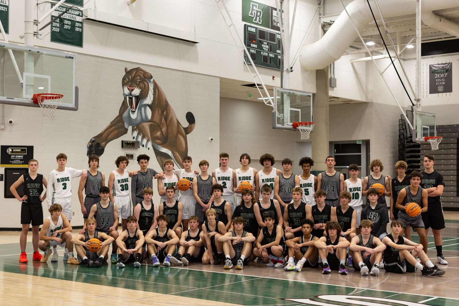 Large group of basketball players posing for team photo in gymnasium.