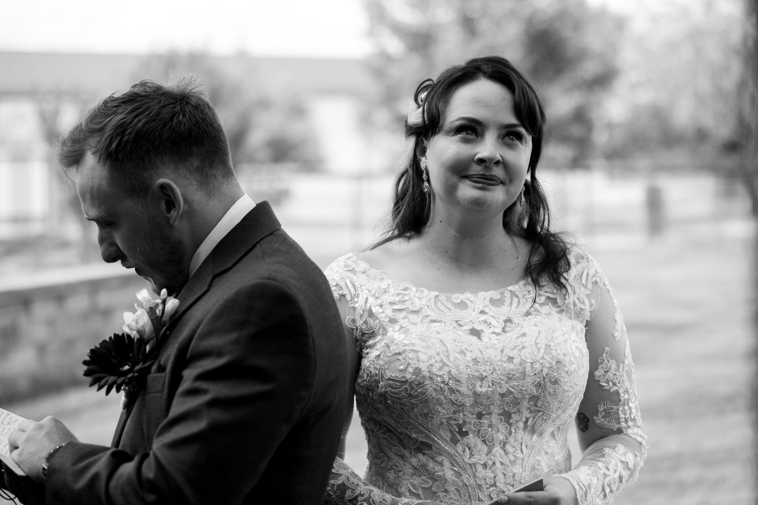 A black and white portrait captures a joyful moment during an outdoor wedding ceremony.
