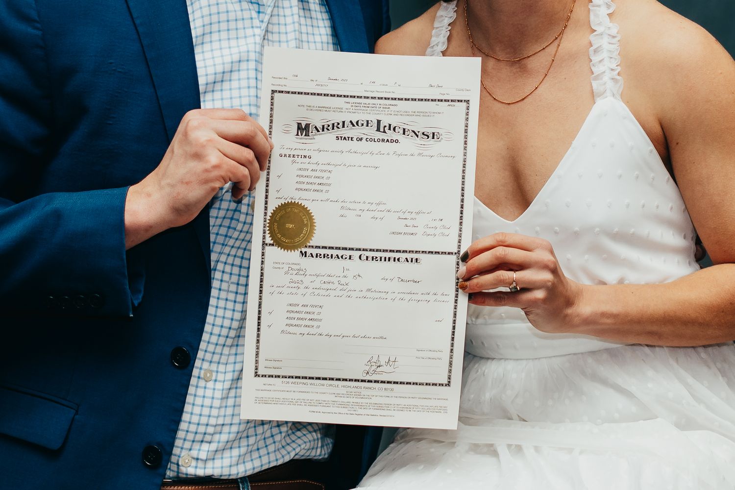 Newlyweds holding up their marriage certificate together during wedding ceremony.