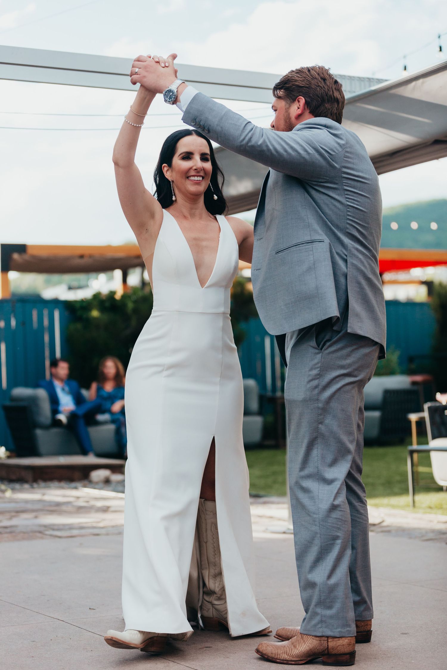 Newlyweds share their first dance together on an outdoor patio.