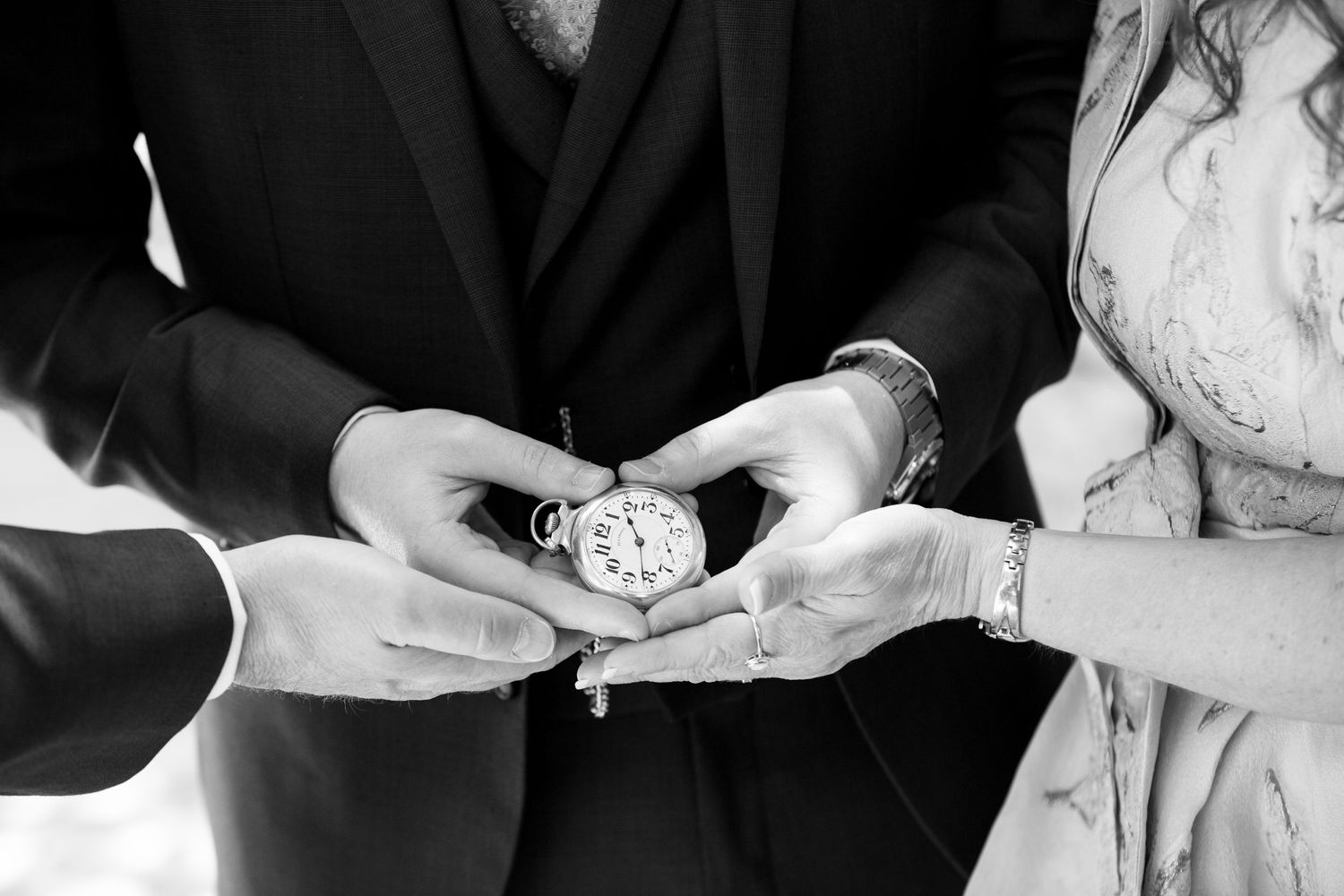Black and white close-up of hands exchanging an antique pocket watch.