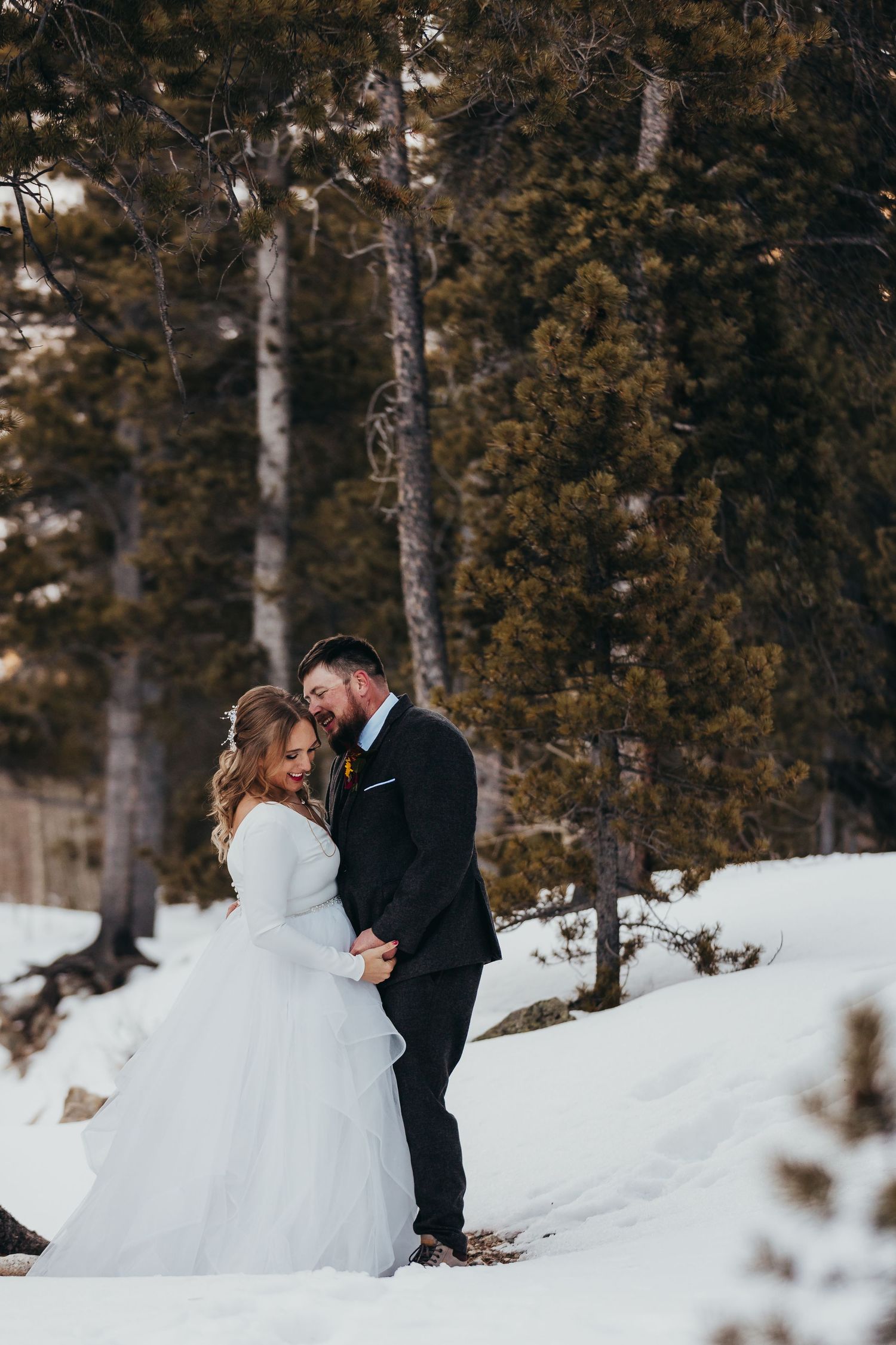 Intimate winter wedding moment captured in snowy forest setting.