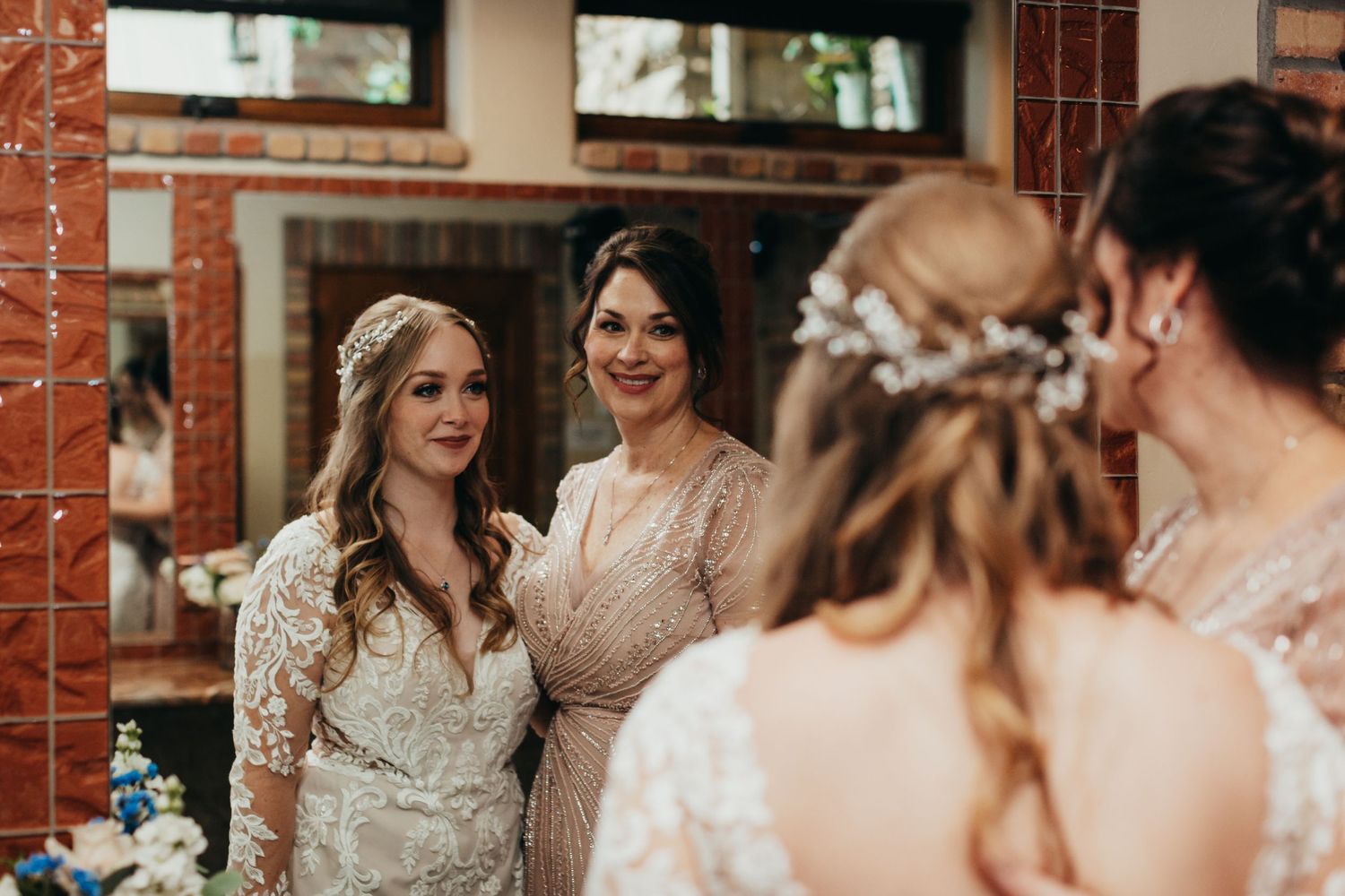 Four women wearing formal dresses gathered together in front of a brick wall.