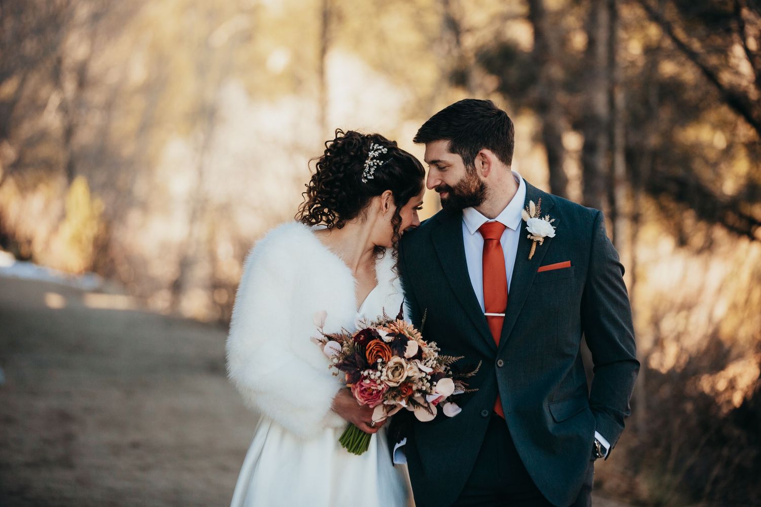 Intimate moment between newlyweds with autumn foliage in background.