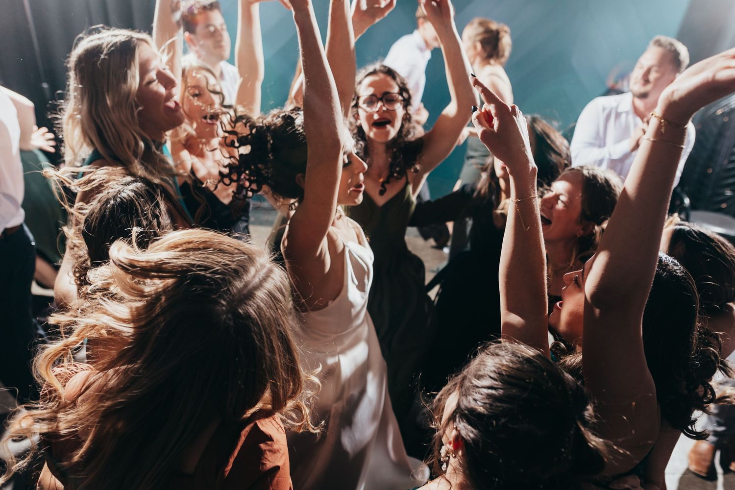 Joyful wedding party dancing with hair flowing in celebratory atmosphere.