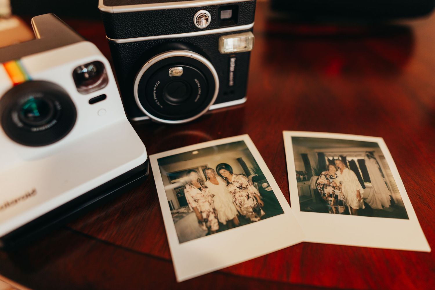 Vintage instant camera with wedding polaroid photos displayed on wooden surface.