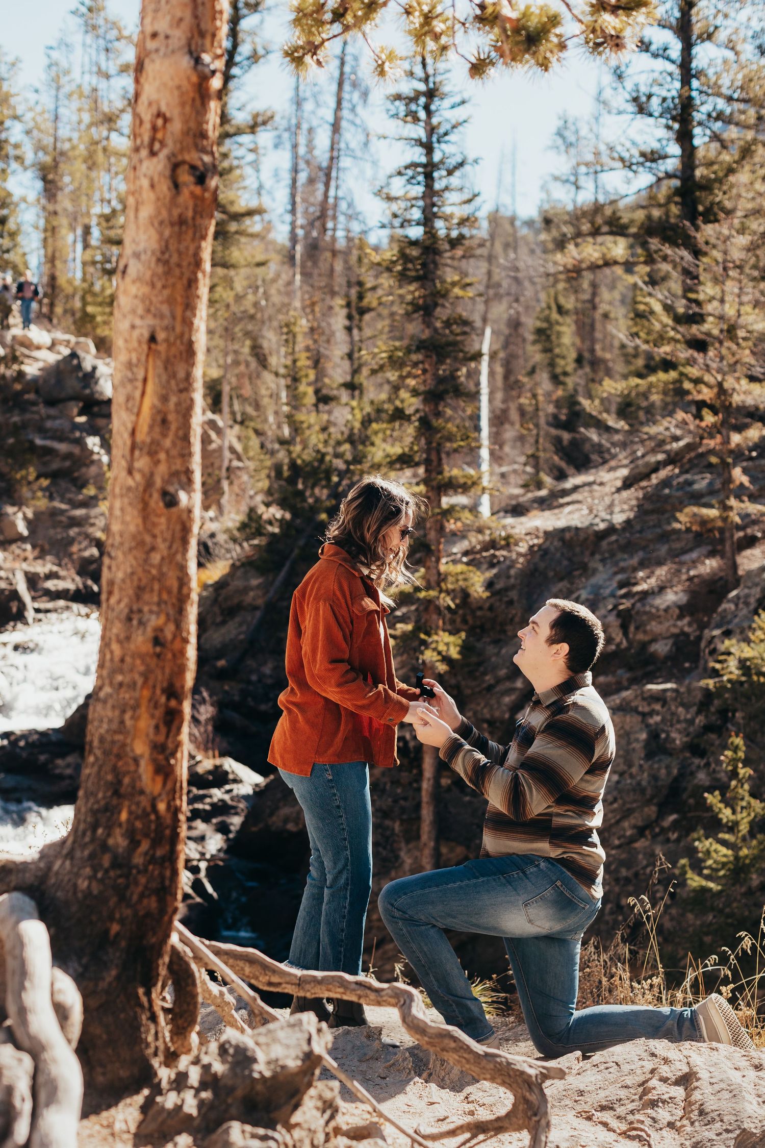Winter proposal moment captured in snowy mountain forest setting.