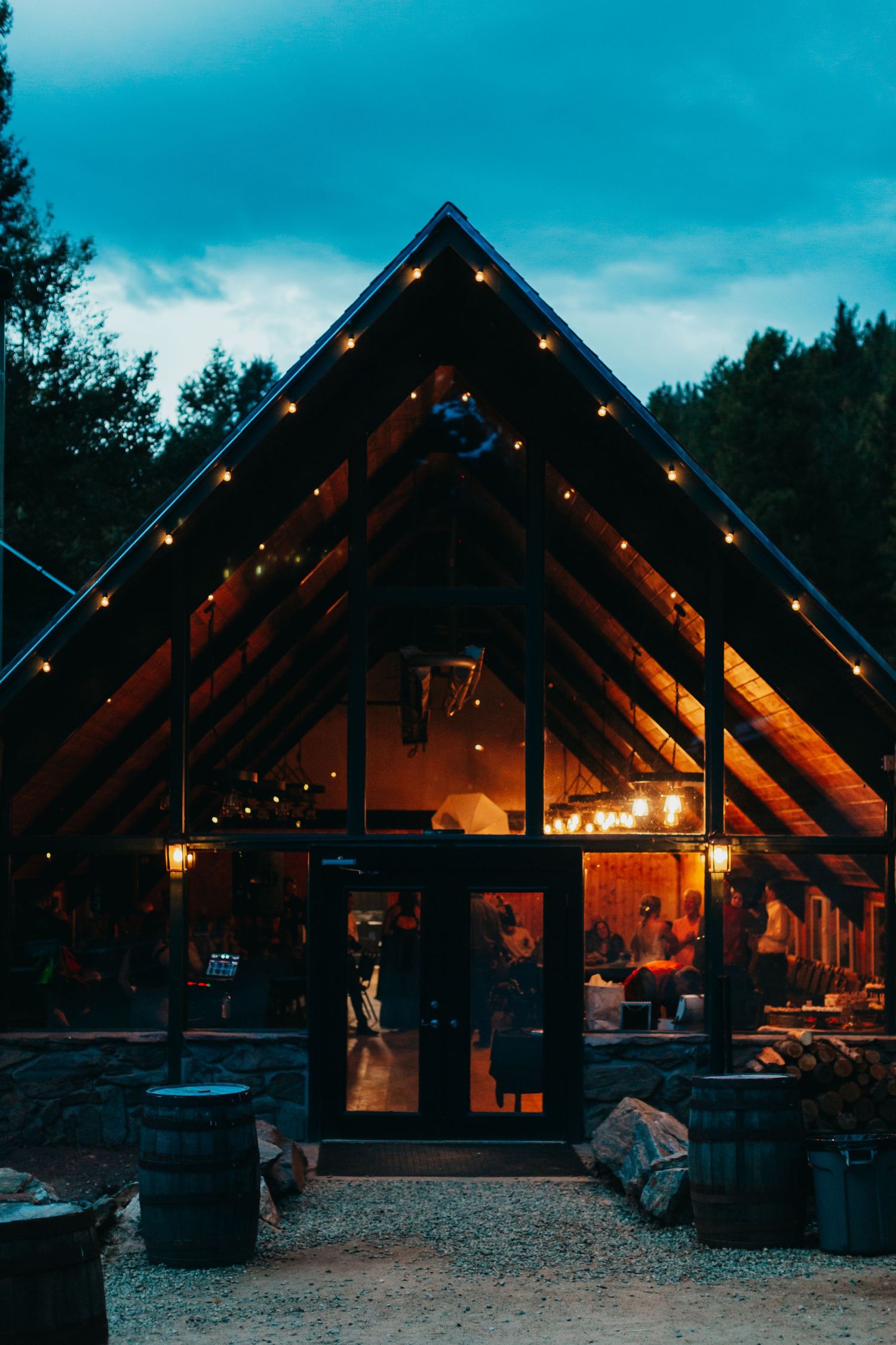 A rustic wooden wedding venue with string lights glowing at dusk.