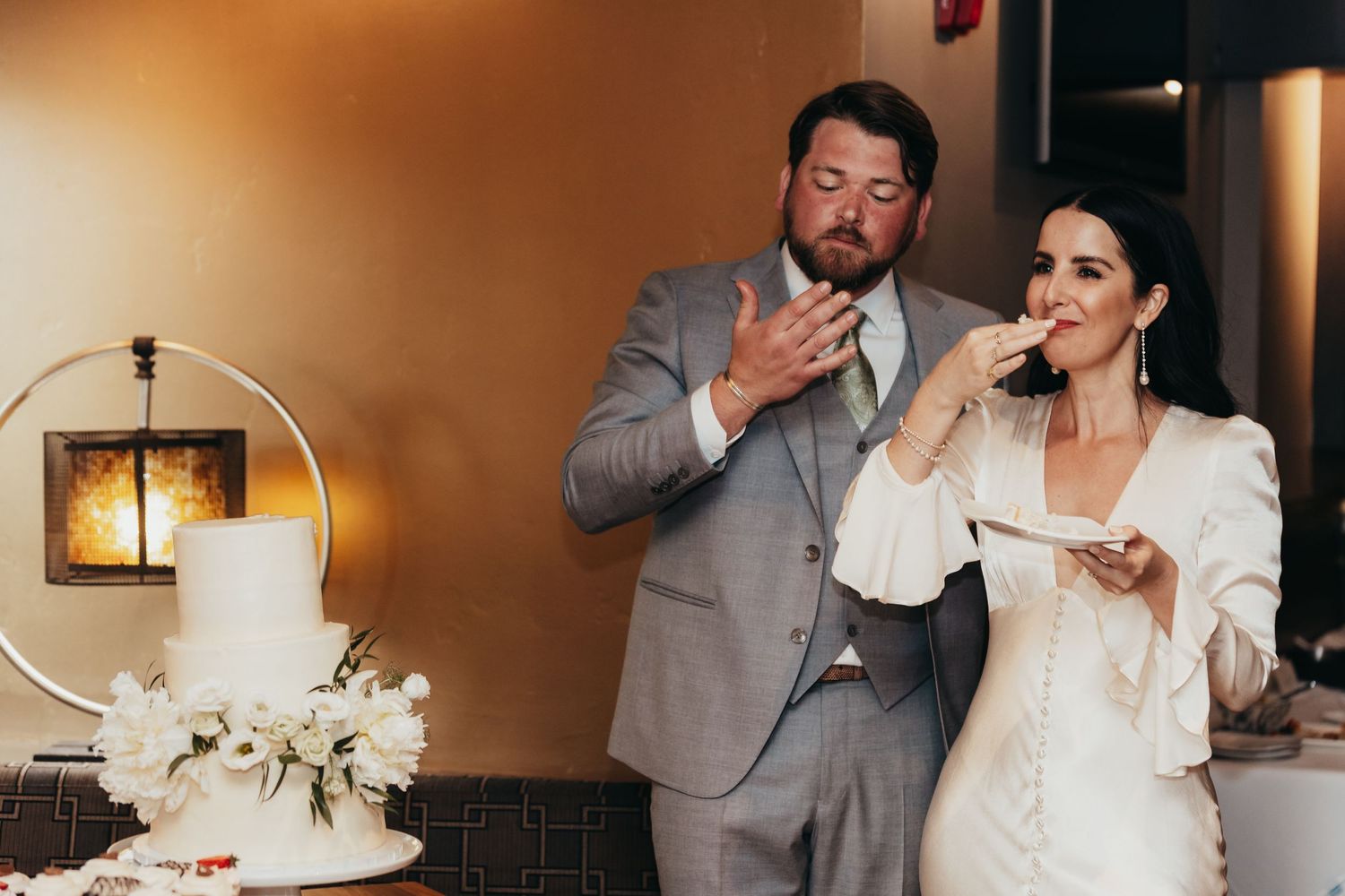 Couple enjoying wedding cake together during reception.