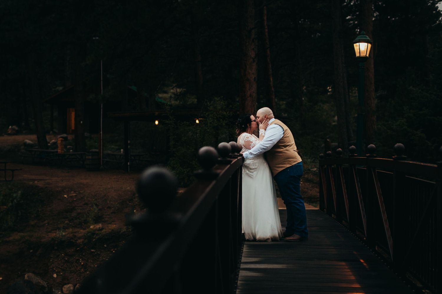 A tender embrace between newlyweds on a dimly lit bridge.