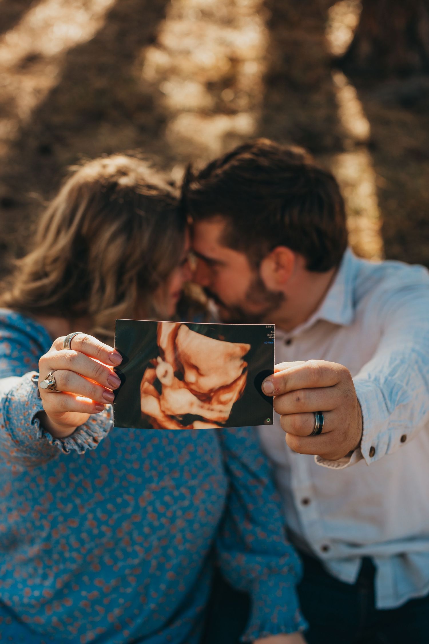 A couple sharing a kiss while holding an ultrasound photo.