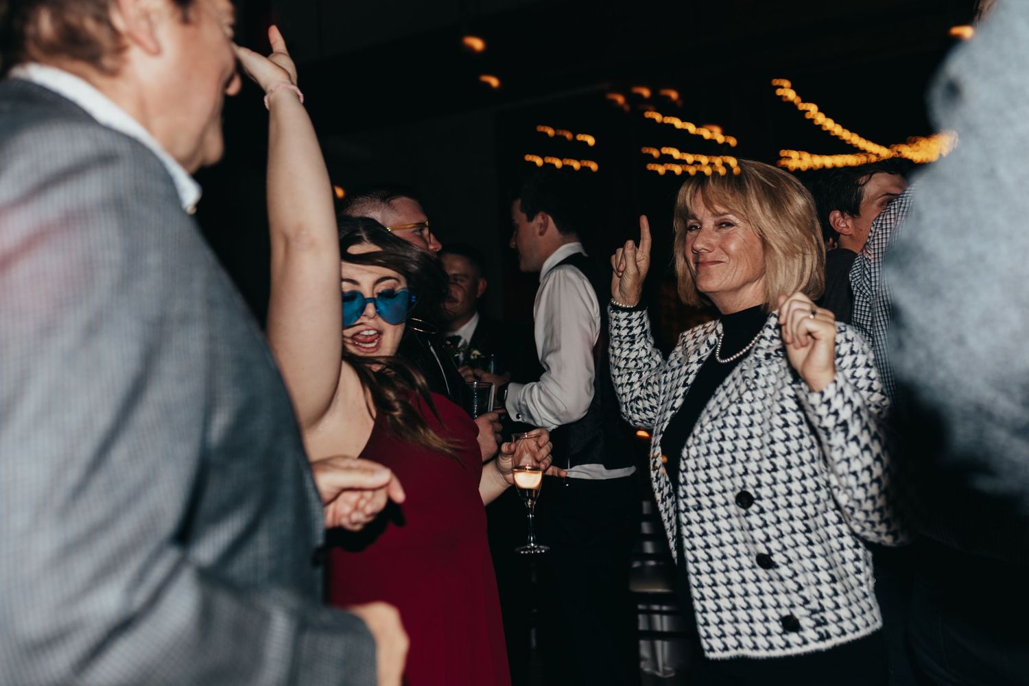 People dancing enthusiastically at a party with blurred lights in the background.