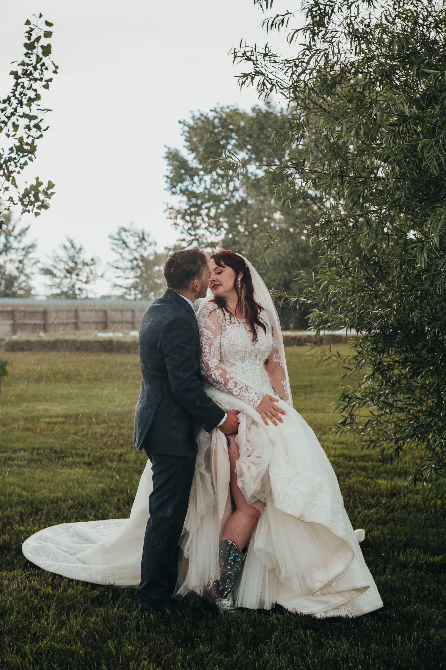 A wedding couple shares an intimate moment outdoors with the bride's dress featuring a high slit.