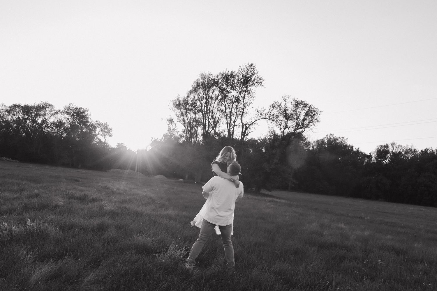 Five black and white landscape photos showing silhouettes and figures against bright glowing sunlight in grassy fields. Sioux Falls.