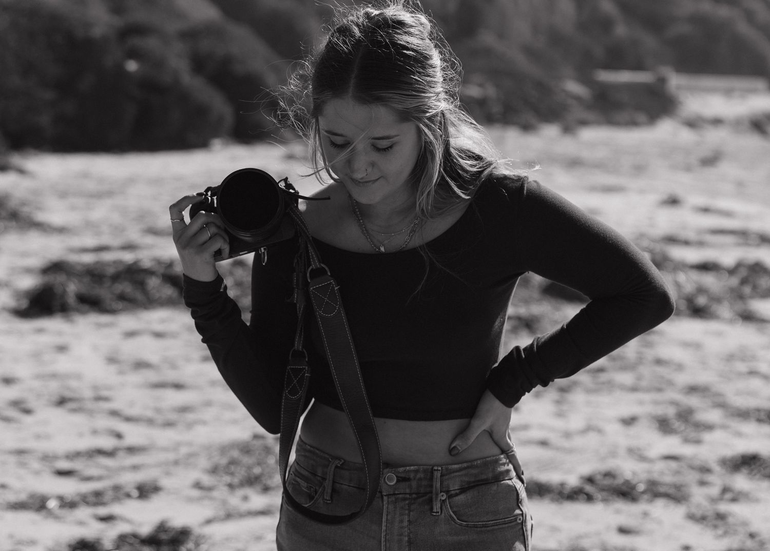 Photographer checking camera settings on rocky coastal beach. Sacramento, California.
