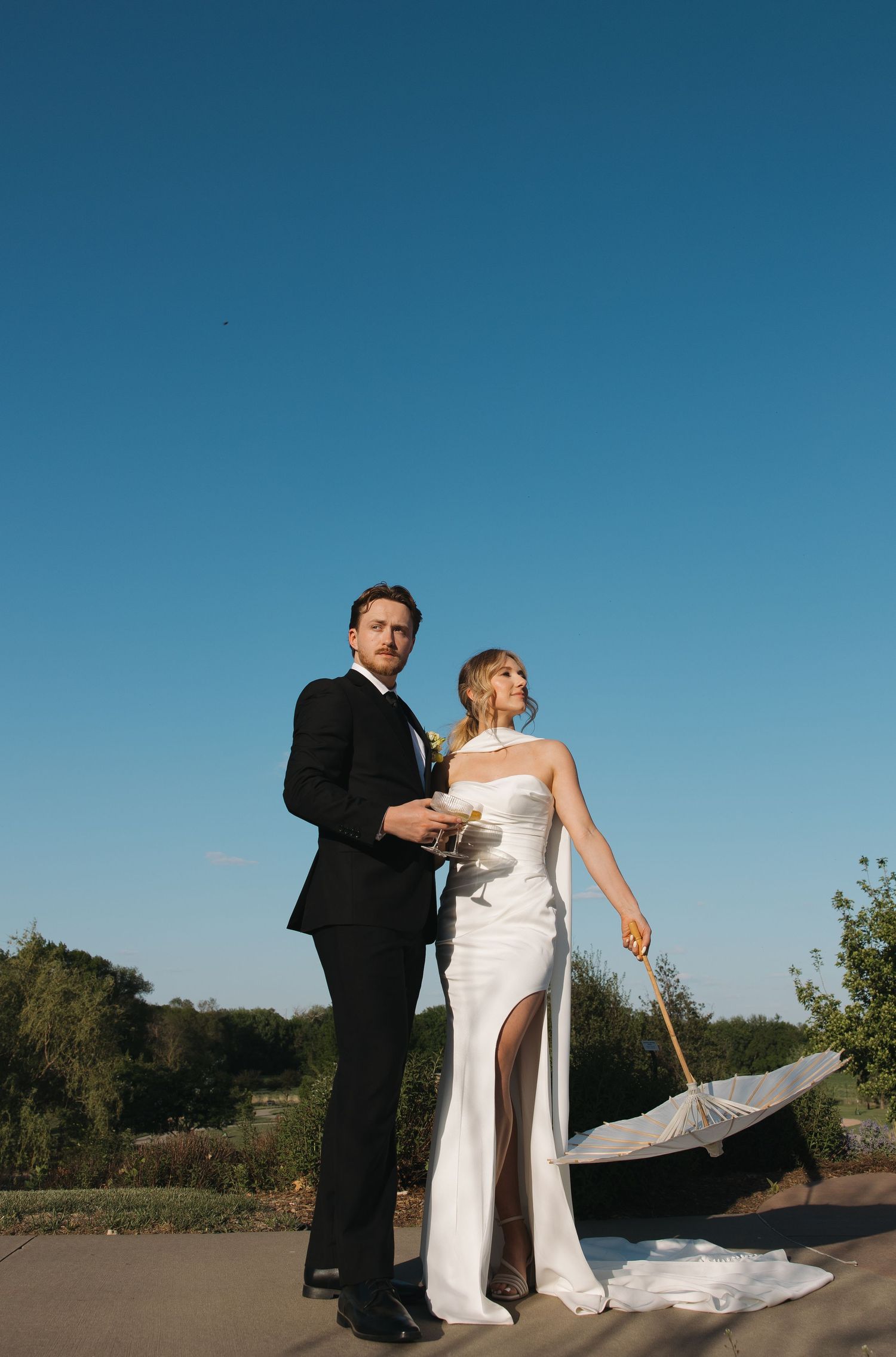 A wedding couple poses dramatically against a bright blue sky. Sioux Falls, South Dakota.