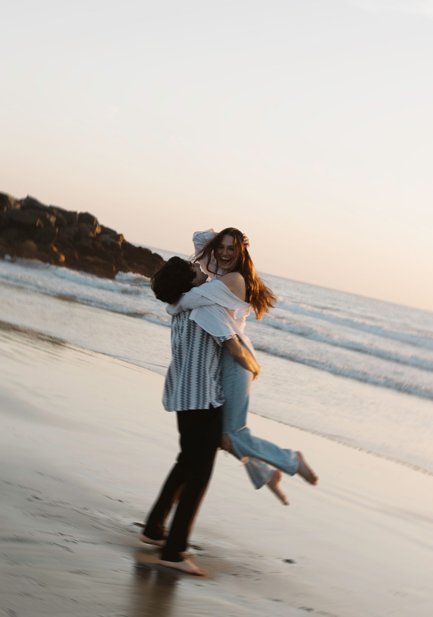 A couple embraces and spins joyfully on a beach at sunset. Sacramento, California. Newport Beach, California.