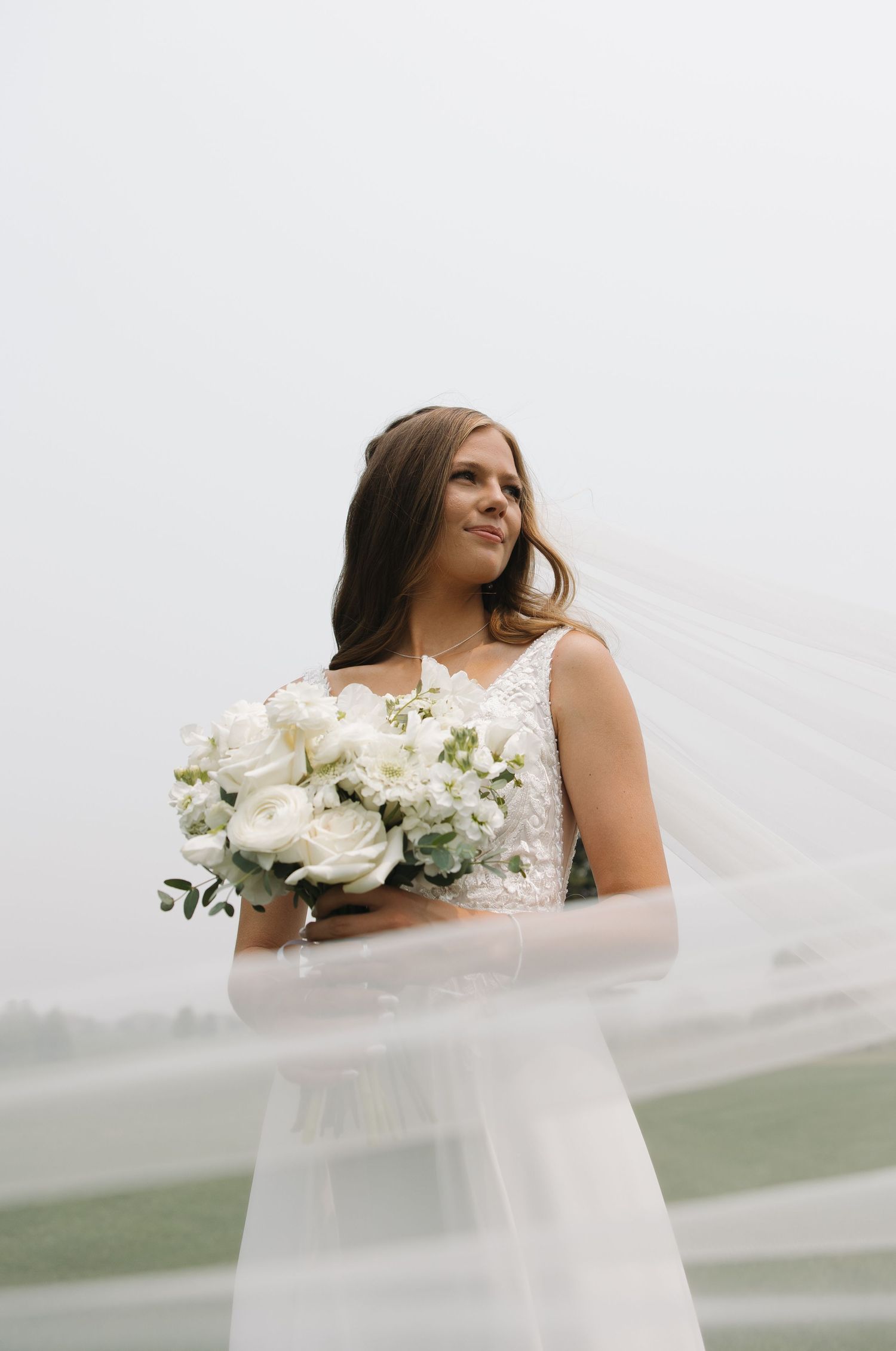 Bride holding beautiful white rose bouquet in a dreamy outdoor setting. Sioux City, Iowa.