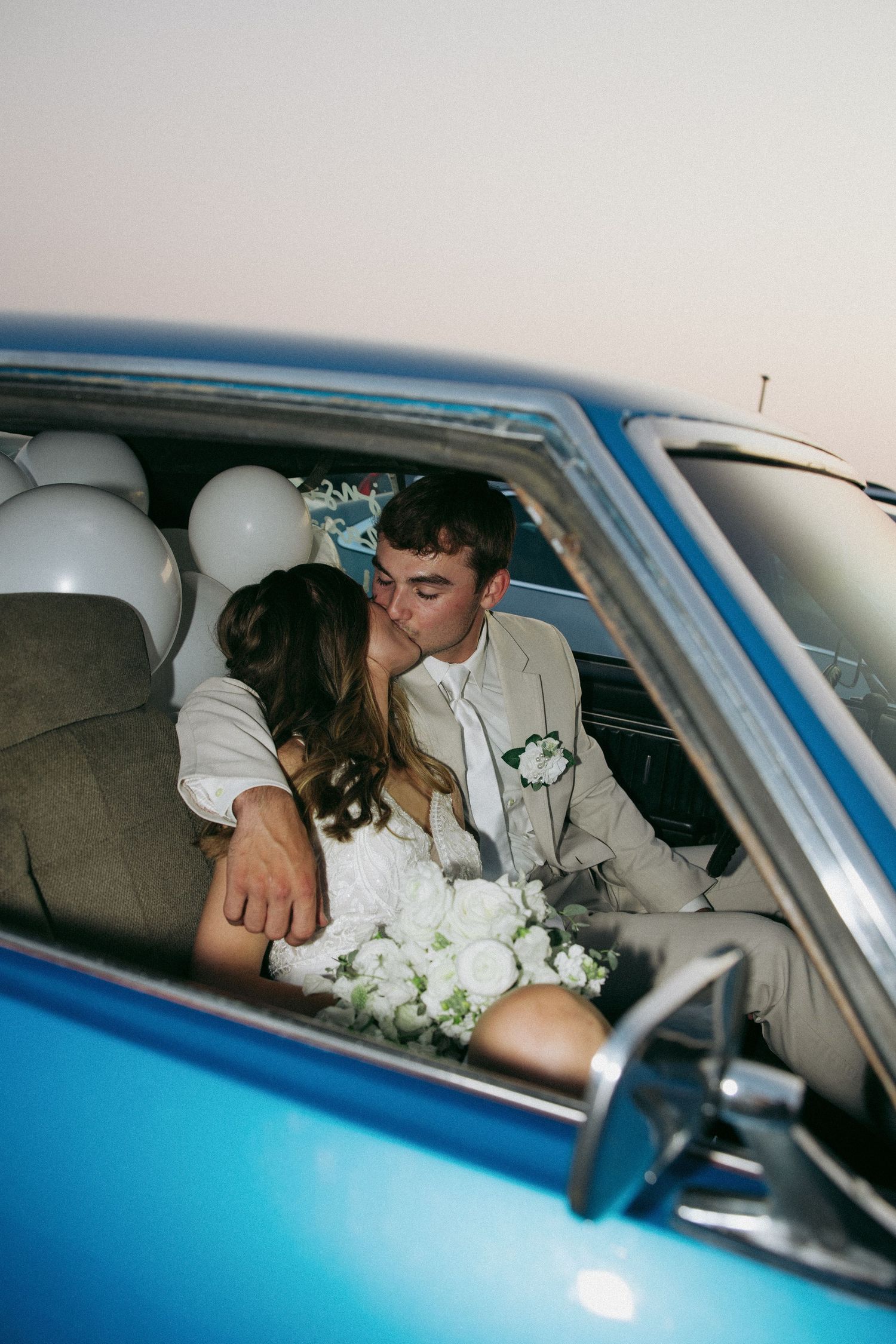 Intimate moment shared in a vintage blue car with white wedding flowers. Sioux City, Iowa.