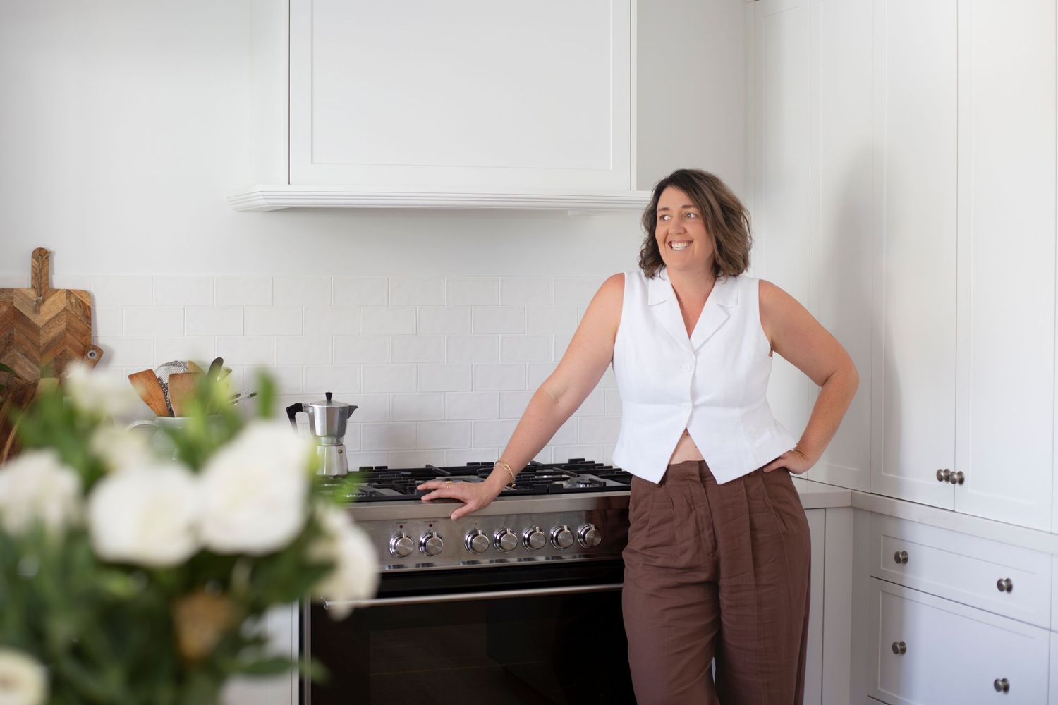 Branding portrait of a woman smiling while seated at her kitchen counter in Rockhampton, styled with a minimal lifestyle aesthetic