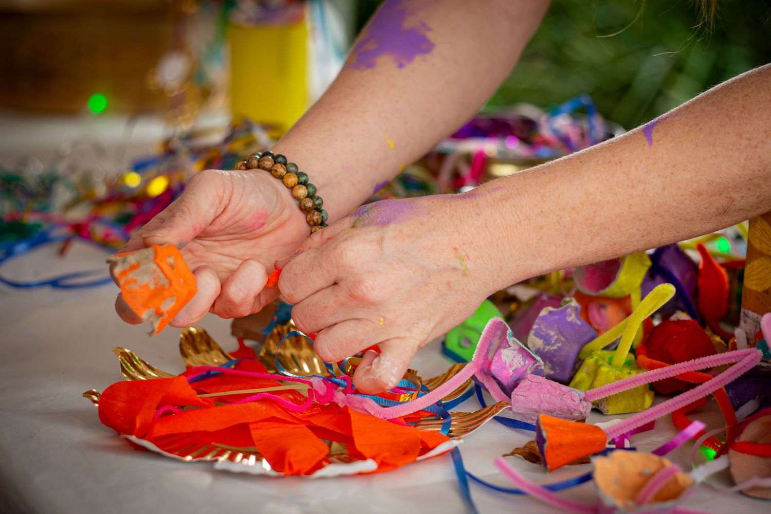Hands assembling a vibrant art activity surrounded by festive decor, captured during a Rockhampton event