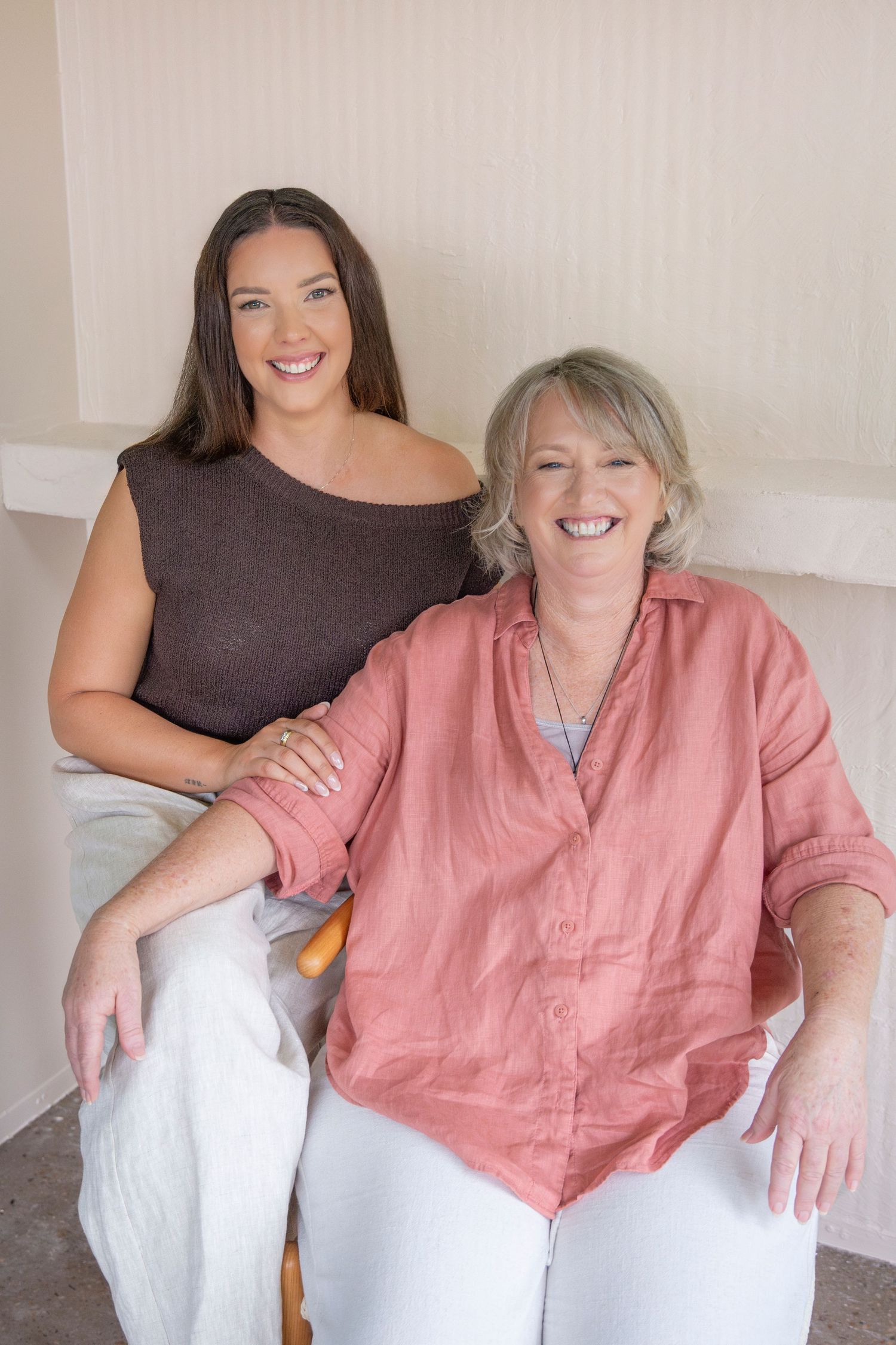 Two women captured in a personal branding shoot with warm, natural light and a minimal setting