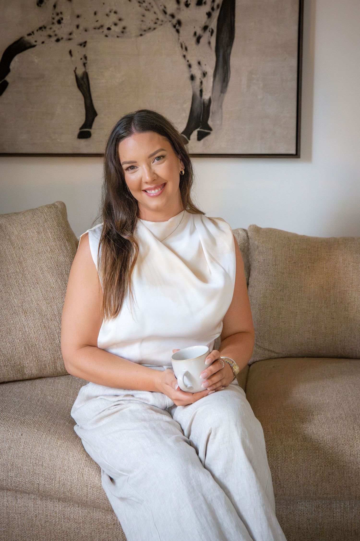 Natural light branding portrait of Yeppoon businesswoman seated on a couch with coffee
