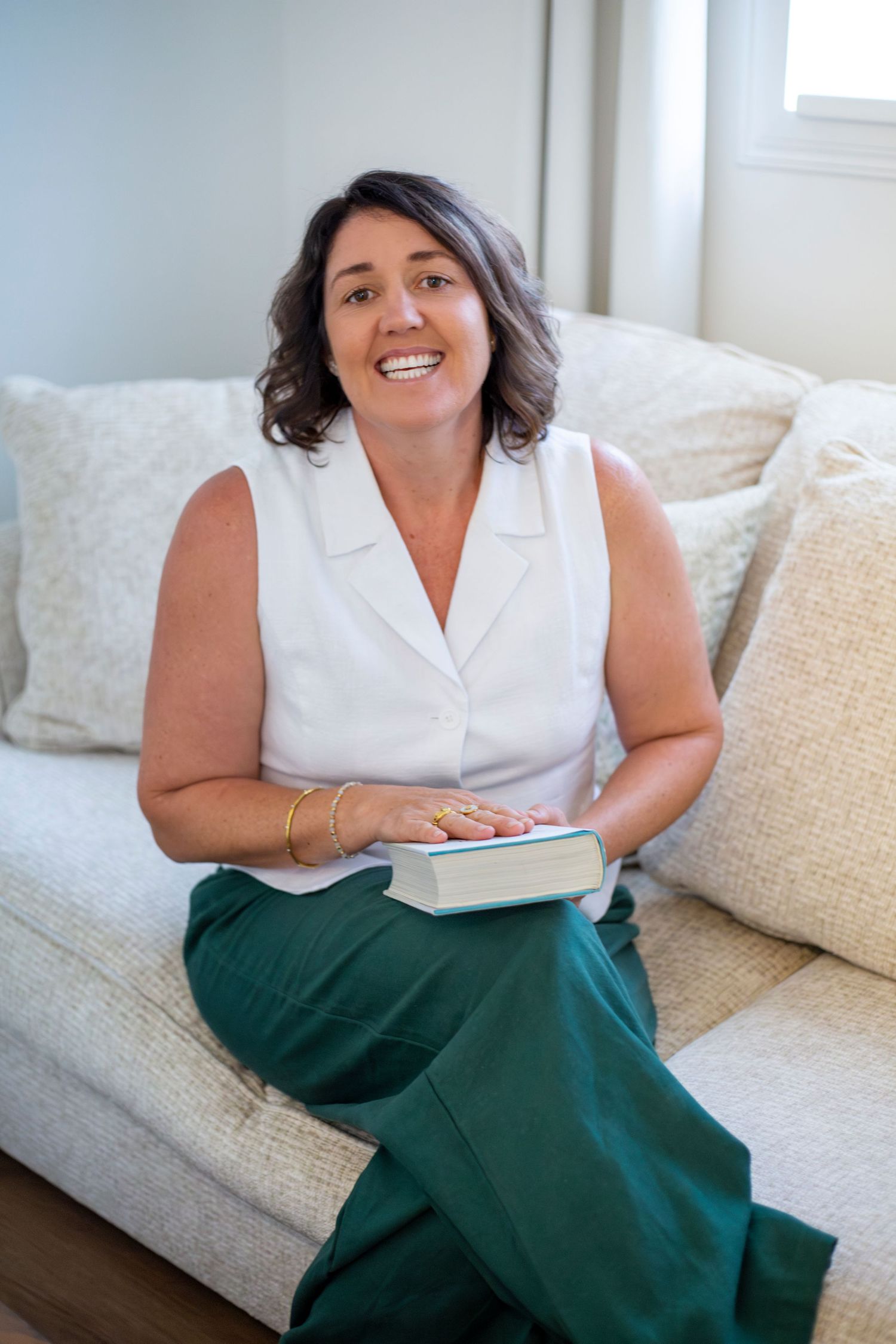 Branding portrait of a woman smiling while seated at her kitchen counter in Rockhampton, styled with a minimal lifestyle aesthetic