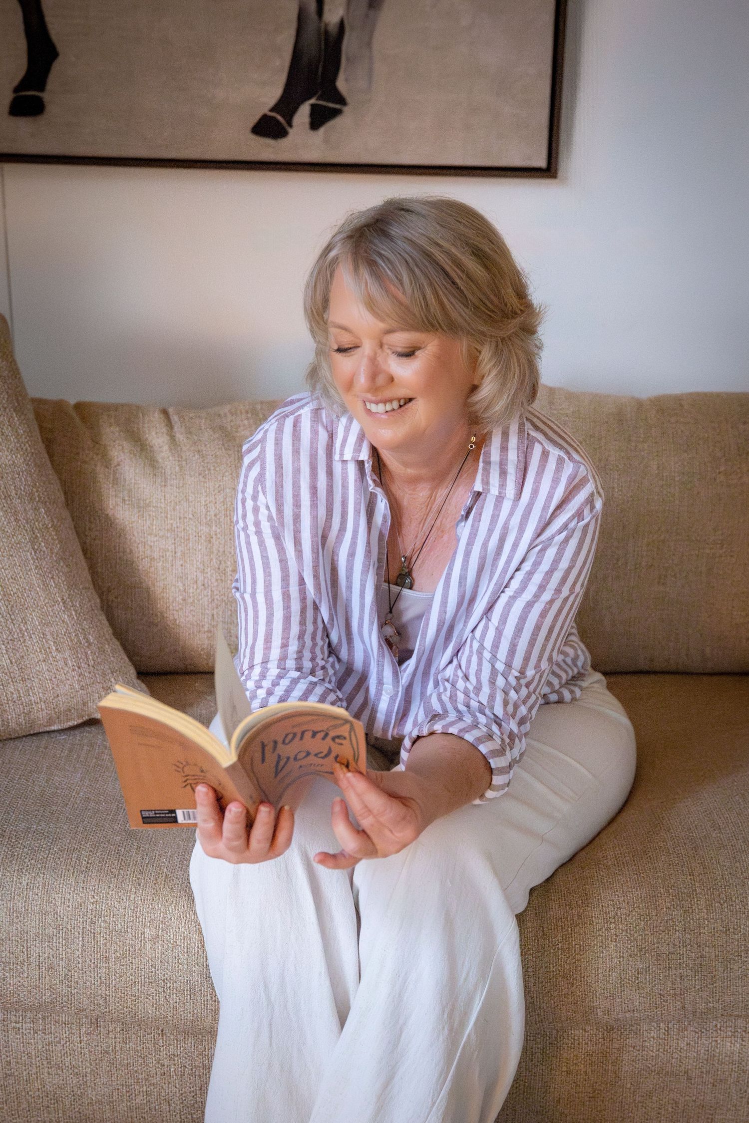 Professional headshot of a woman sitting on a couch reading in natural light, captured in a Rockhampton studio