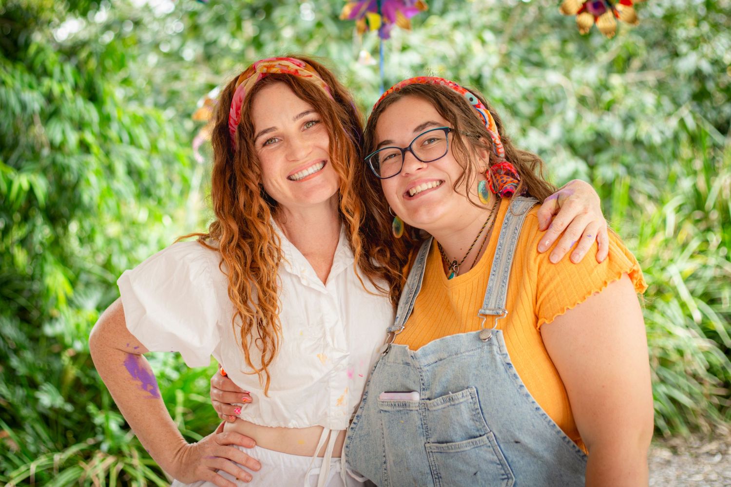 Two women posing and smiling at an outdoor event in Rockhampton with greenery in the background