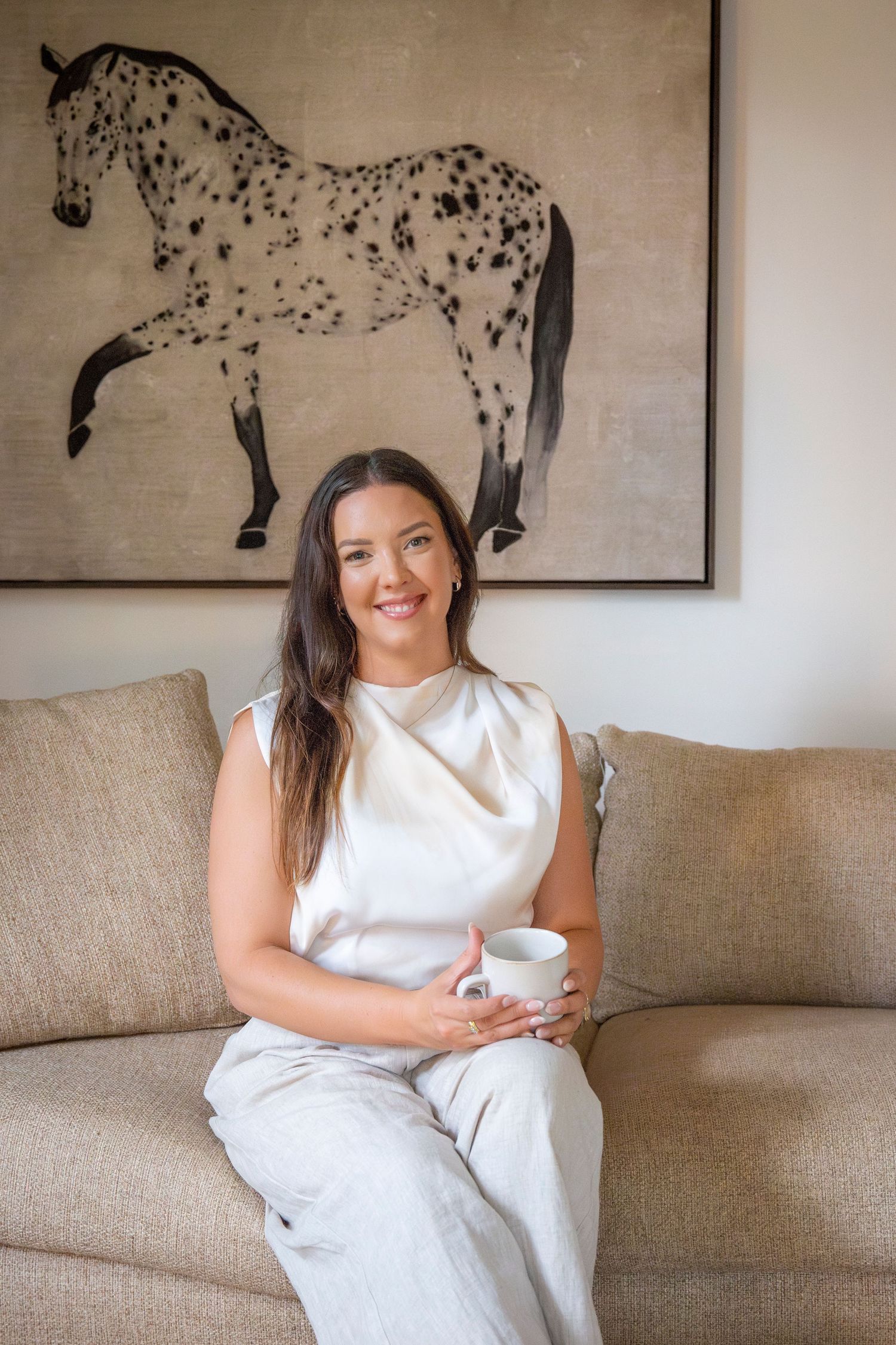 Natural light branding portrait of Yeppoon businesswoman seated on a couch with coffee