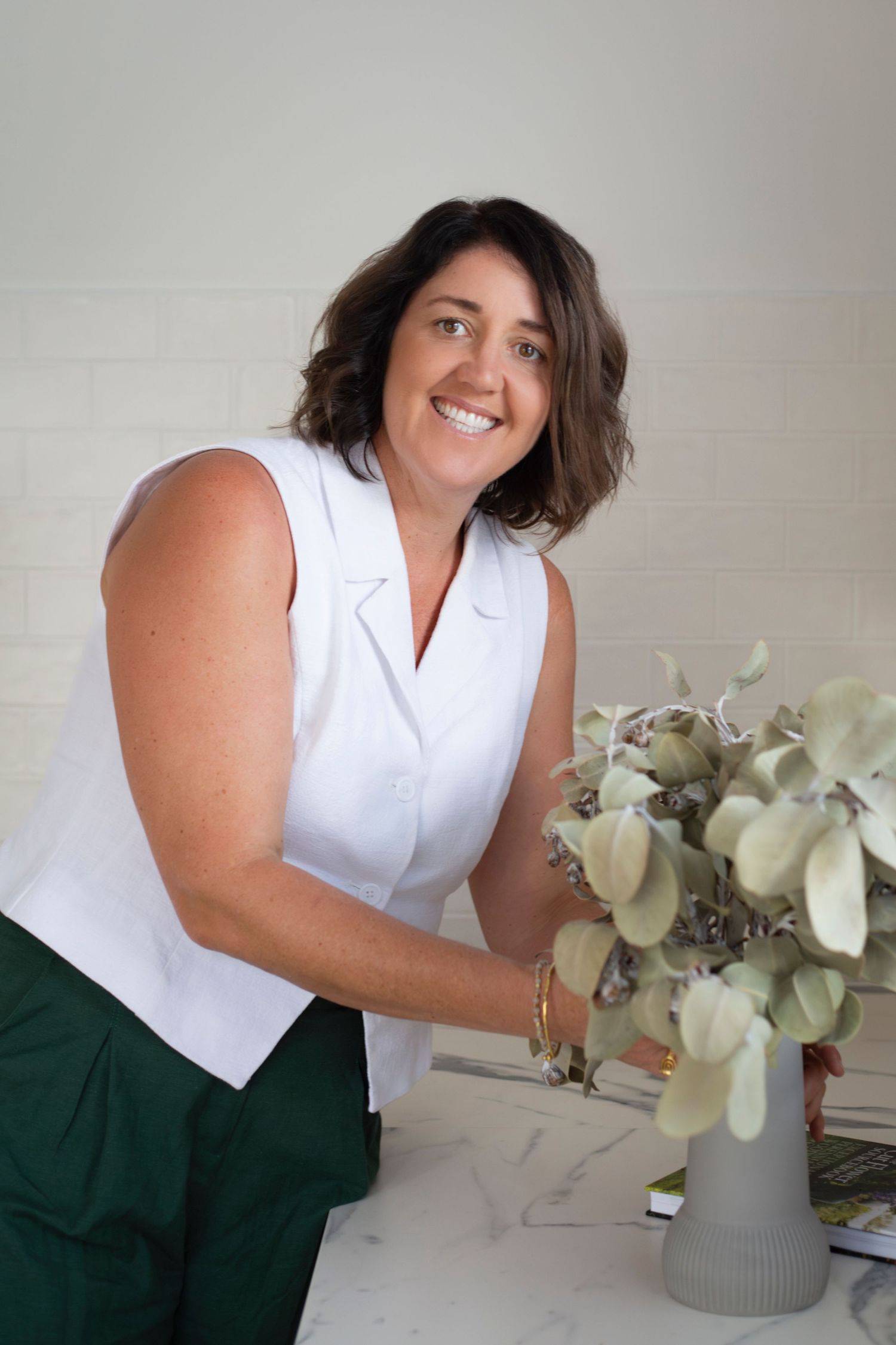 Branding portrait of a woman smiling while seated at her kitchen counter in Rockhampton, styled with a minimal lifestyle aesthetic