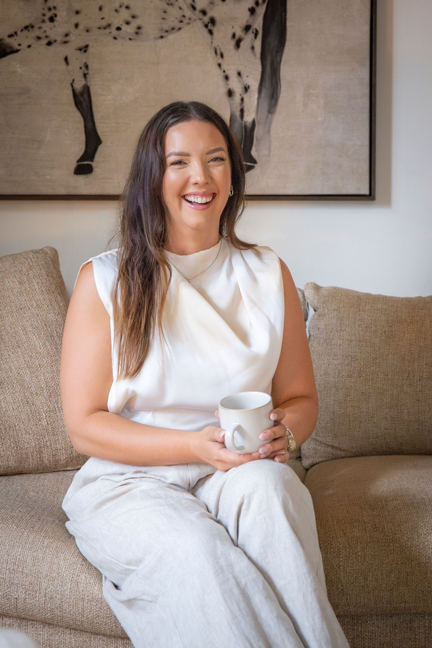 Natural light branding portrait of Yeppoon businesswoman seated on a couch with coffee