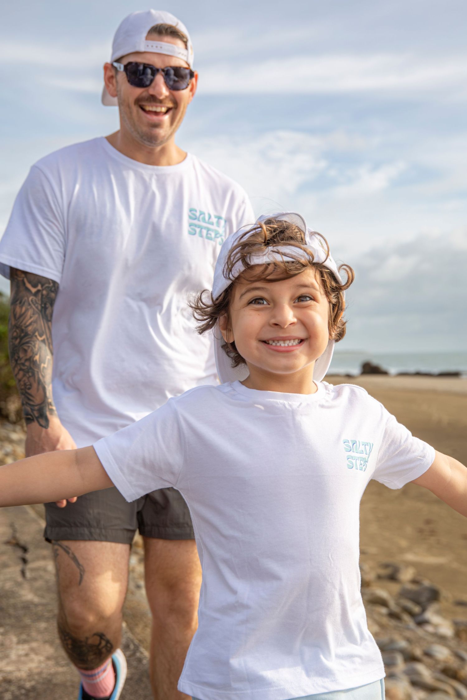 Smiling Father and Son wearing Salty Steps branding hats and Shirts