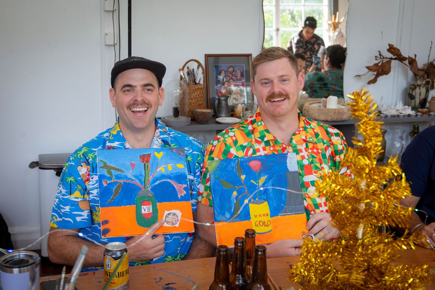 Two men in matching blue floral shirts enjoying drinks at a festive Christmas event in Rockhampton