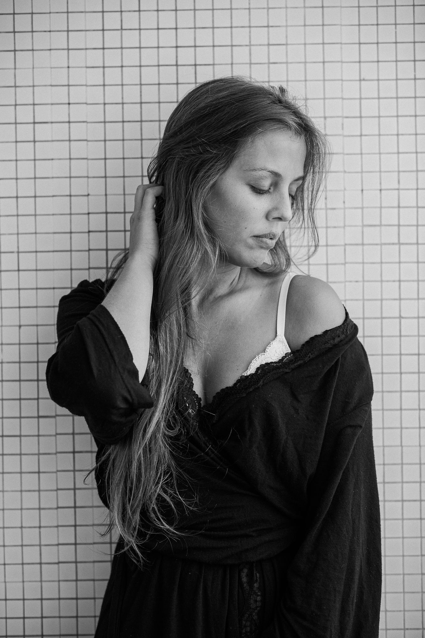 Black and white photo series showing a person in a dark top against a tiled wall, captured in multiple poses.