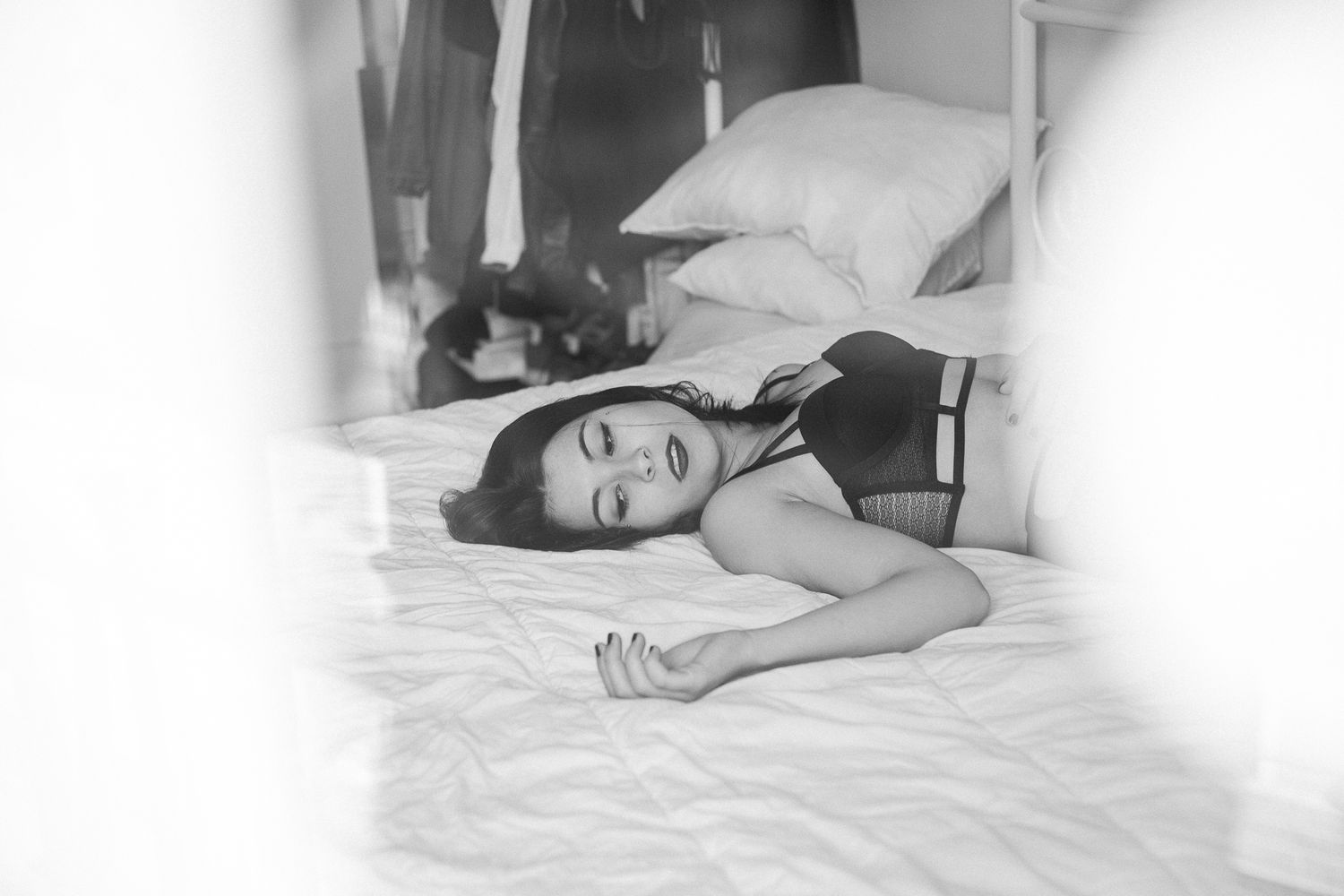 A person lying peacefully on white bedding in a bright, minimalist bedroom setting.