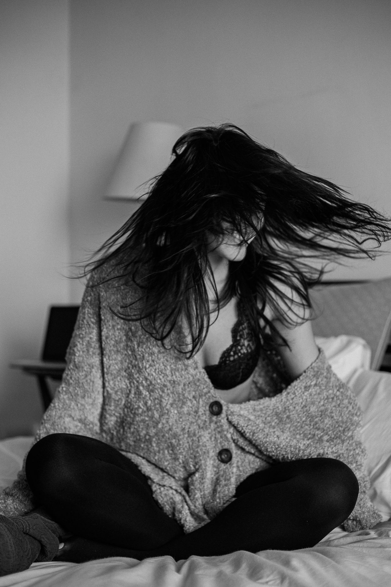 A series of black and white photos showing someone with dark hair lying down in a gray sweater against white bedding.