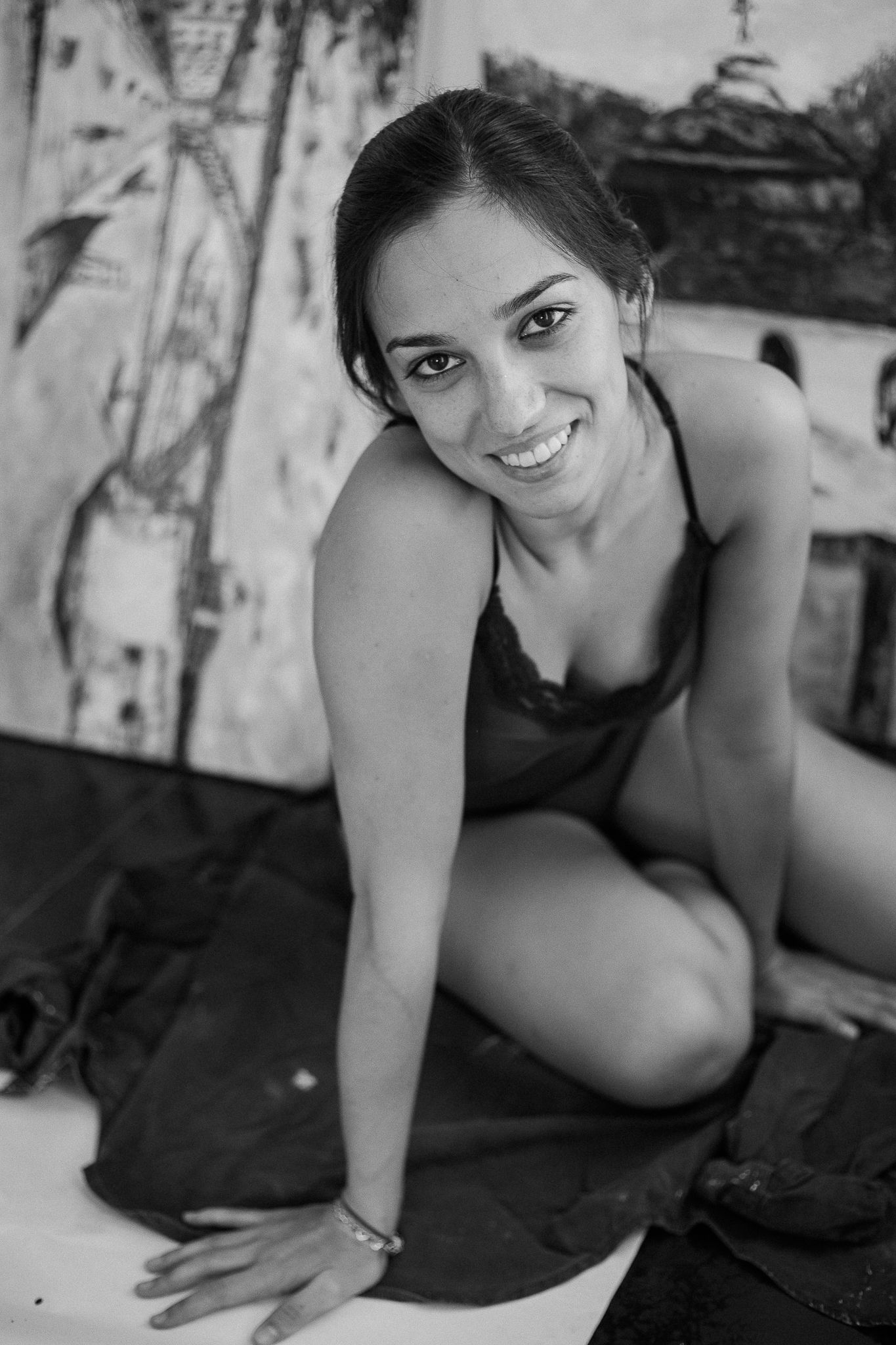 A black and white photo series showing a woman in dark clothing posing on the ground with a warm smile.
