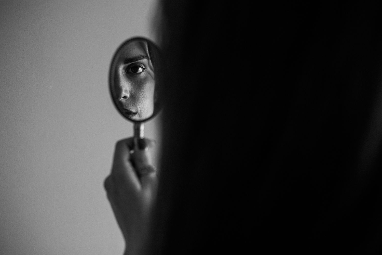 A dramatic black and white portrait shows a person's silhouette against a dark background with dramatic lighting.