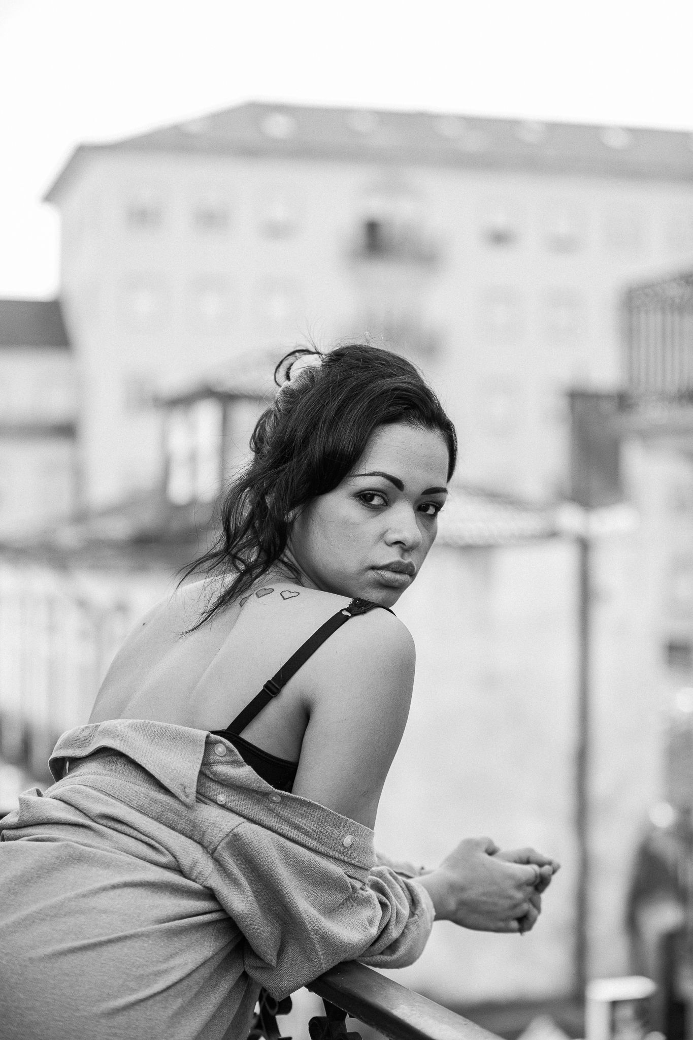 Moody black and white portraits showing a figure gazing over an urban balcony.