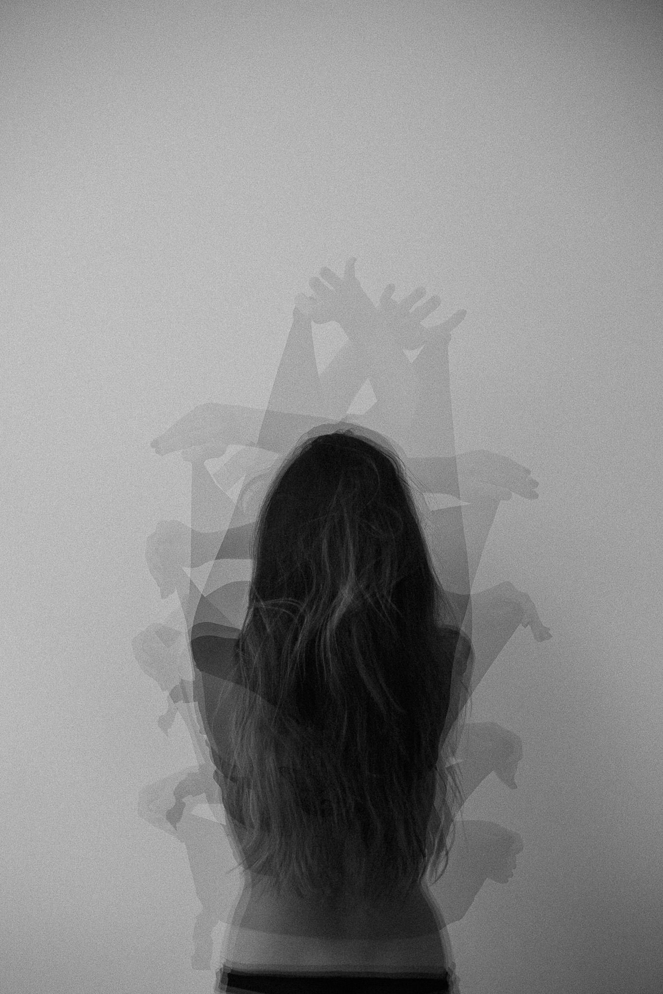 Minimalist grayscale silhouette study showing shadowy figures against plain background.