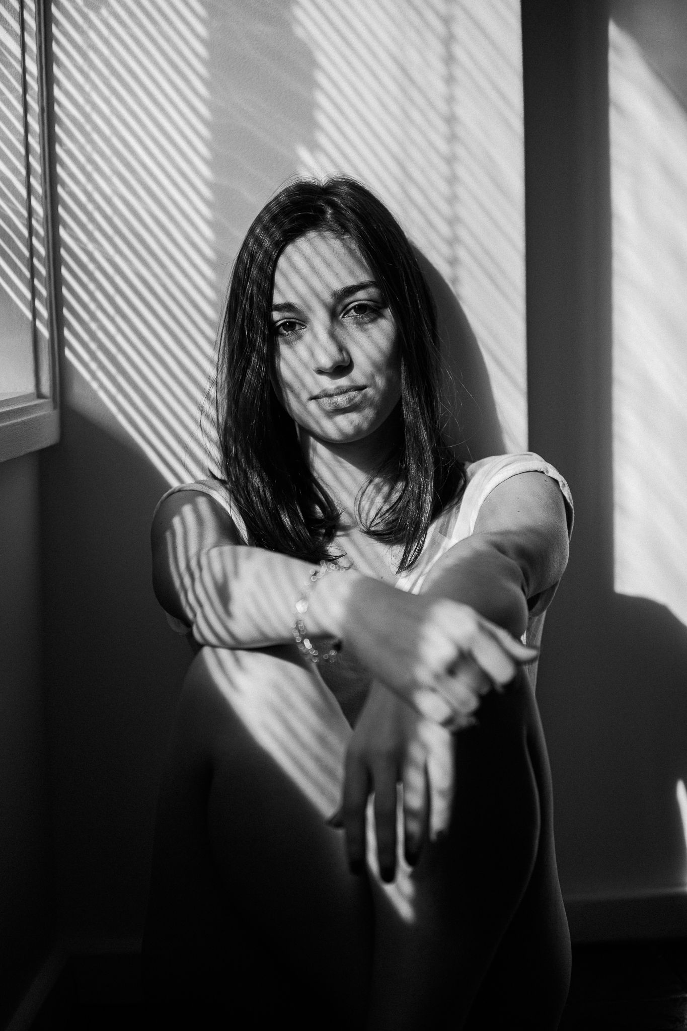 A series of black and white portraits showing a figure in dramatic window light with diagonal shadows creating a moody effect.