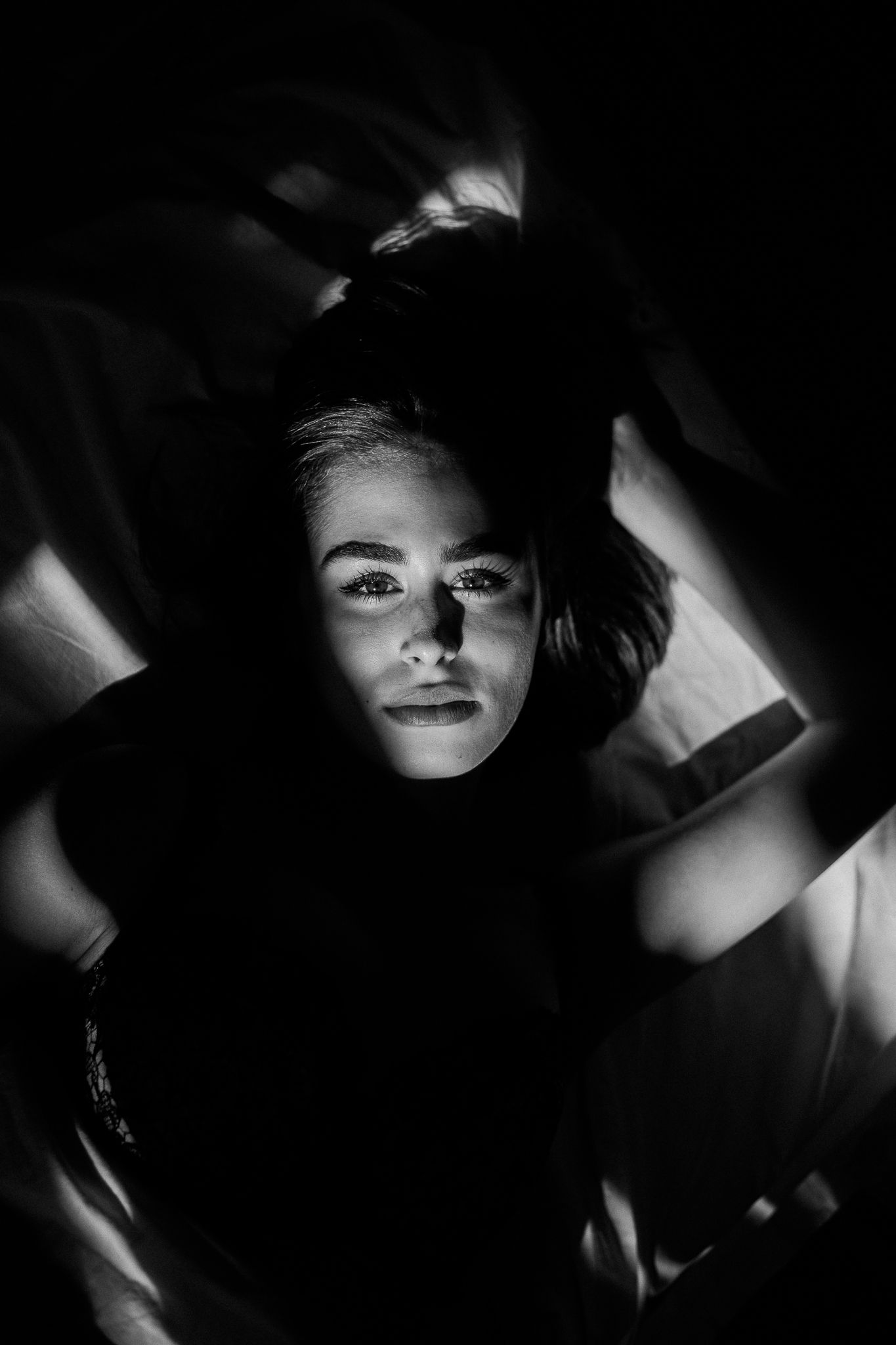 Dramatic black and white portrait series showing faces partially illuminated in shadow with moody film noir lighting.