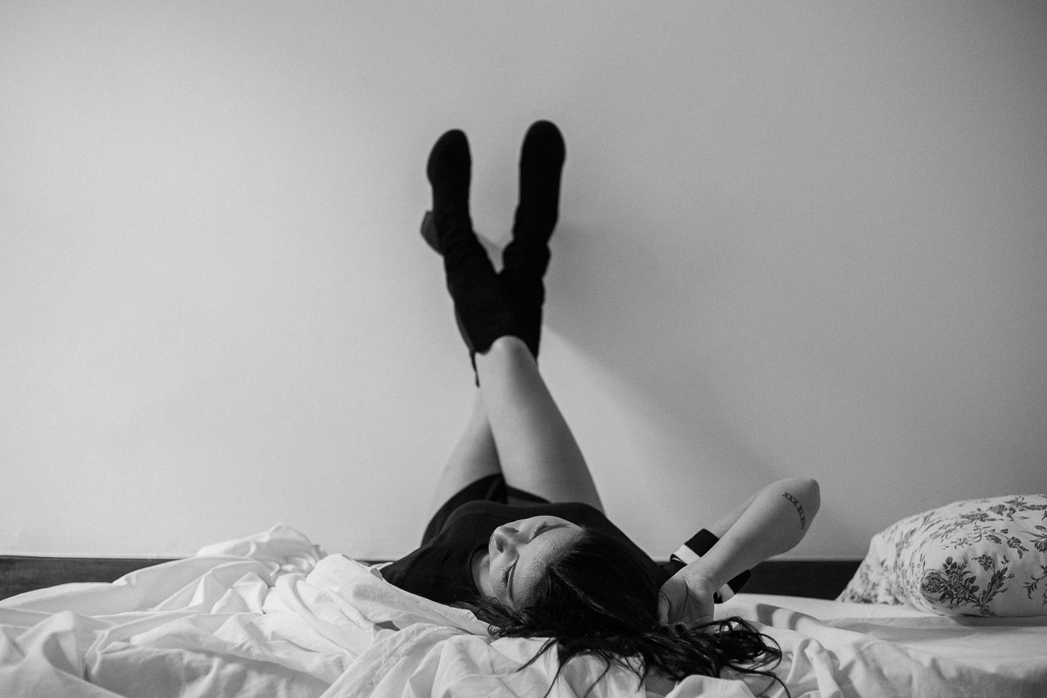 A series of black and white photos showing someone lying on white bedding in different reclining poses.